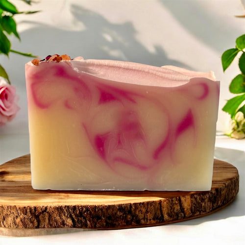Bar of soap with pink swirls on a wooden board with a natural background