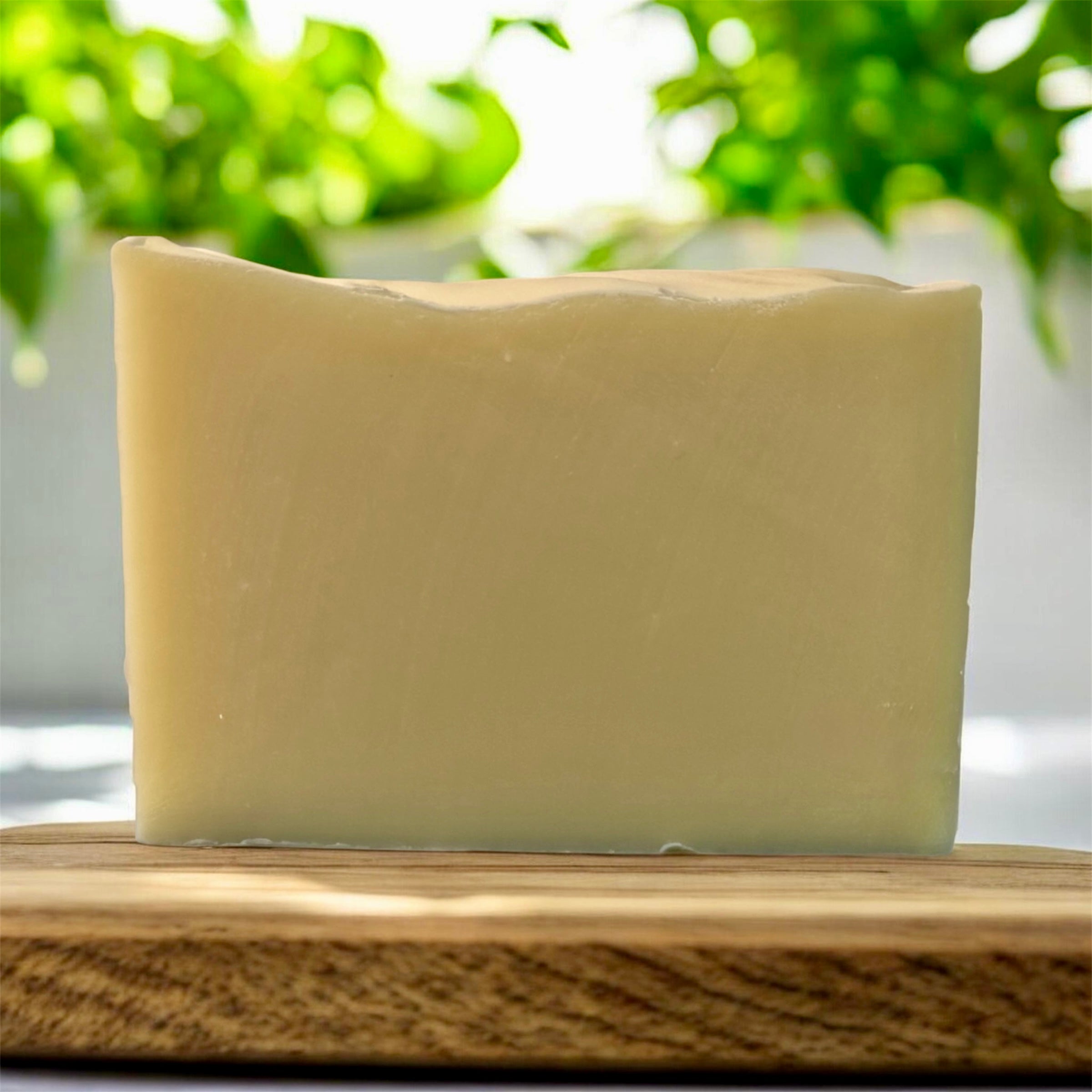 Bar of soap on a wooden surface with a blurred green plant background